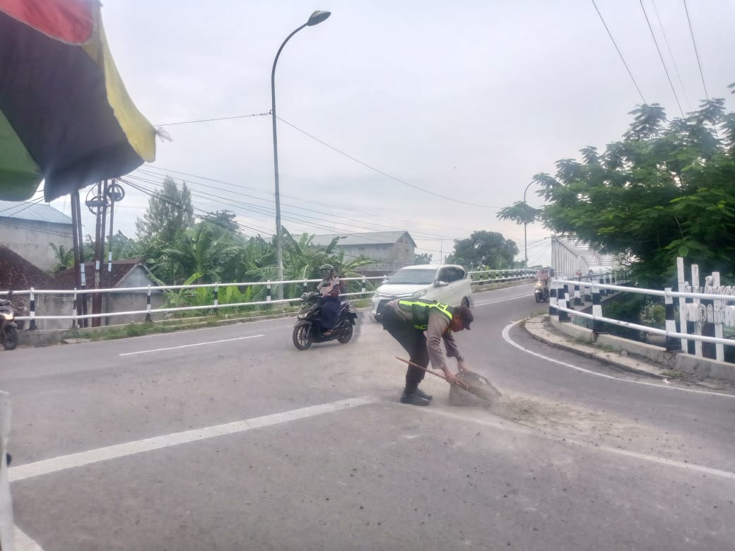 Respon Cepat Personil Polsek Padangan Bersihkan Tumpahan Pasir dan Krikil di Jalan Raya