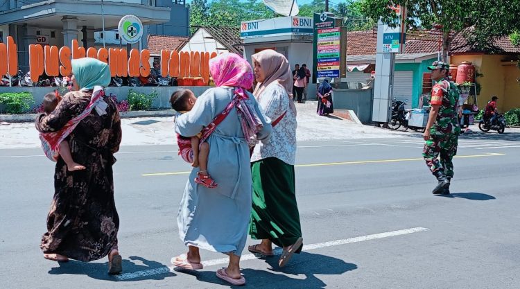 Aksi Spontan Babinsa Ranuyoso, Bantu Warga Menyebrang Jalan di Tengah Padatnya Arus Lalu Lintas di Lumajang