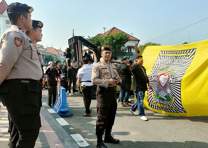Bendera pesilat Persaudaraan Setia Hati Terate (PSHT) dibentangkan di depan aparat kepolisian yang berada di depan Mapolrestabes Surabaya. (Foto: Wendy Setiawan)