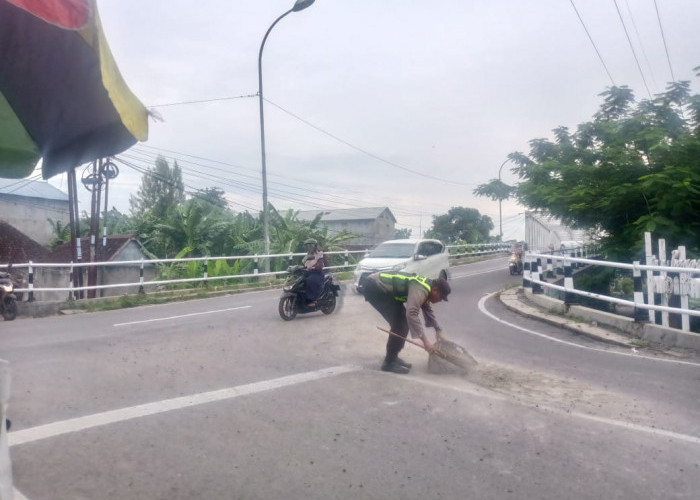 Respon Cepat Personil Polsek Padangan Bersihkan Tumpahan Pasir dan Krikil di Jalan Raya