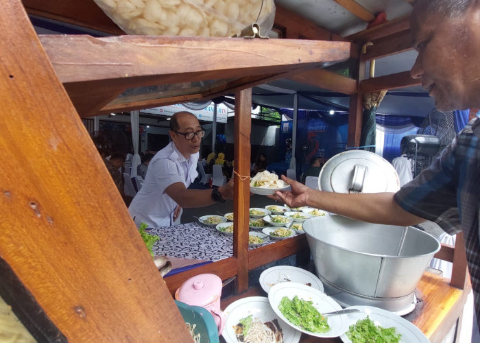 Salah satu anggota Satpol PP mengambil pesanan tahu campur di open house HUT ke 54 Memorandum